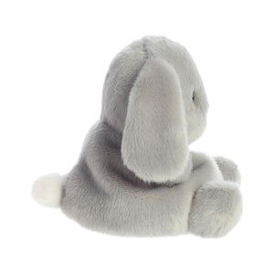The Twice as Sweet Palm Pal Pebbles Bunny features cuddly, soft slate-grey fur, floppy ears, and a small white tail, sitting sideways against a white background.