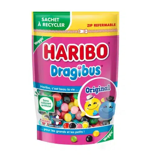 A vibrant pouch of Twice as Sweet Haribo Dragibus (France) chewy candy, set against a pink background, displays smiling cartoon candies and assorted colorful treats through a clear window on the front.