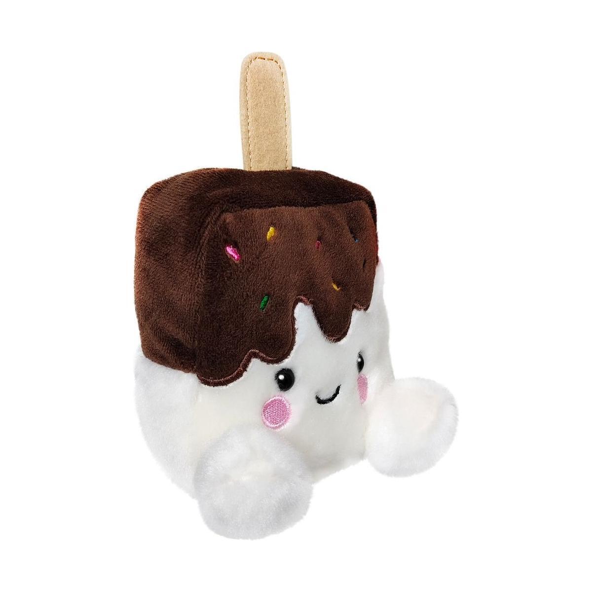 The Palm Pal Dolce Ice Cream Bar by Twice as Sweet is a plush toy shaped like an ice cream bar, featuring a chocolate-dipped top, colorful sprinkles, tan stick, smiling face with rosy cheeks, and fluffy white arms—ideal for summer fun!.