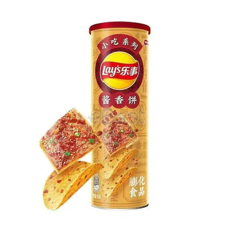 A 90g can of Twice as Sweet Lay’s Aroma Sauce Pancake Flavour Chips (China) features yellow packaging with Chinese text. Two curved and two square, seasoned chips topped with red and green spices showcase this limited-edition snack.