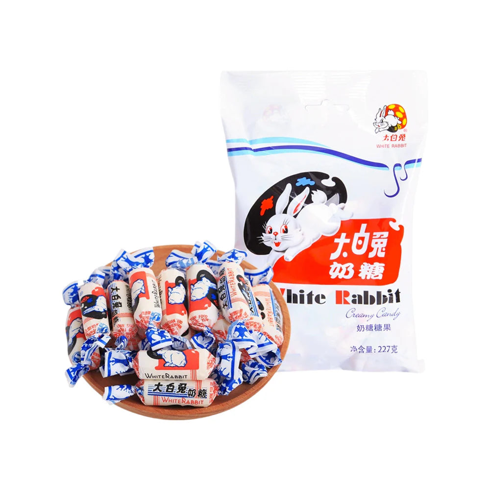 A wooden bowl with White Rabbit Creamy Candy by Twice as Sweet sits beside an unopened 227g bag from China, featuring a white rabbit illustration and bilingual text, highlighting this classic treat.